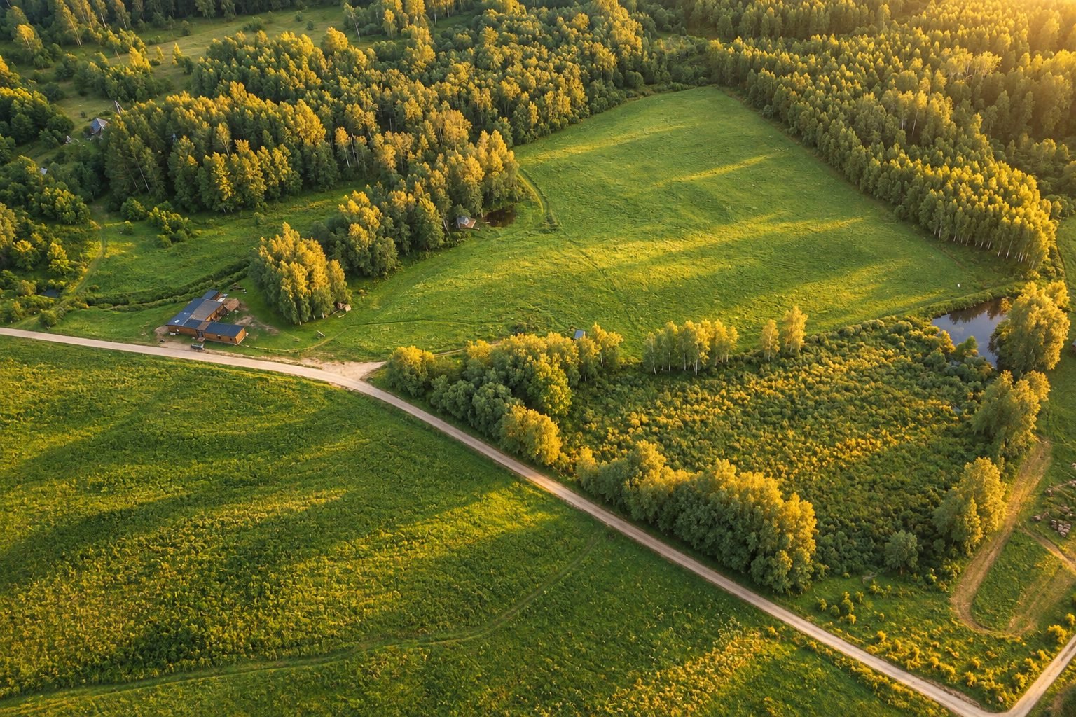 Šviesų slėnio sklypas, pievos ir kelias saulėlydžio šviesoje iš drono